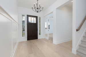 Foyer with stairway, light wood-type flooring, and a chandelier