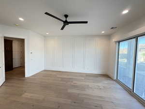 Empty room featuring light wood-style floors, a ceiling fan, recessed lighting, and a decorative wall