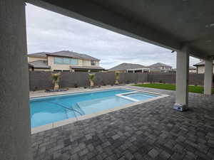 View of pool with a patio area, a fenced backyard, and a pool with connected hot tub