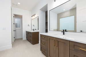 Full bathroom featuring two vanities, recessed lighting, and light tile patterned floors