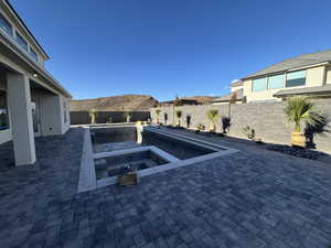 View of pool featuring a patio, a fenced backyard, a mountain view, and a pool with connected hot tub
