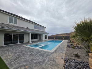 View of pool with a fenced backyard, a pool with connected hot tub, and a patio