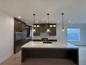 Kitchen with dark brown cabinets, light stone counters, hanging light fixtures, glass insert cabinets, and recessed lighting