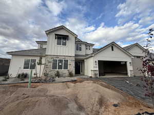 Craftsman-style house with board and batten siding, decorative driveway, stone siding, and an attached garage