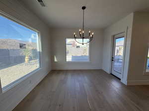 Unfurnished dining area with dark wood-style floors, a chandelier, plenty of natural light, and wooden walls