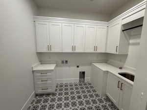 Washroom featuring hookup for an electric dryer, hookup for a washing machine, cabinet space, and light flooring