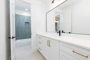 Bathroom with vanity, tub / shower combination, and light tile patterned floors