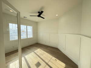 Unfurnished room featuring a decorative wall, wainscoting, light wood finished floors, ceiling fan, and recessed lighting