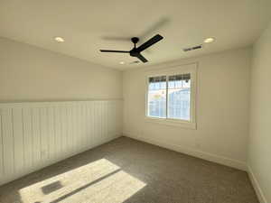 Spare room with a ceiling fan, carpet floors, wainscoting, and recessed lighting
