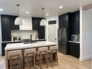 Kitchen featuring dark cabinets, decorative backsplash, stainless steel appliances, and recessed lighting
