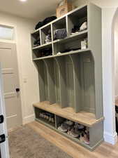 Mudroom with arched walkways and light wood finished floors