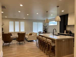 Kitchen with a kitchen island with sink, gas stove, recessed lighting, pendant lighting, and a kitchen bar