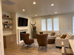 Living area featuring recessed lighting, a fireplace, and light wood-style flooring