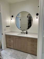 Bathroom featuring light marble finish floors, vanity, and a spacious closet
