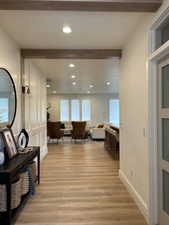 Corridor with light wood-style flooring, recessed lighting, a decorative wall, and beam ceiling