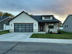 View of front of house with stone siding, a front lawn, a porch, concrete driveway, and an attached garage