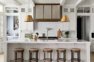 Kitchen featuring glass insert cabinets, white cabinetry, decorative backsplash, and beamed ceiling