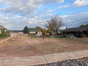 Fenced backyard with a trampoline, a playground, and a storage shed