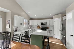 Kitchen featuring recessed lighting, lofted ceiling, green cabinets, stainless steel appliances, and decorative backsplash