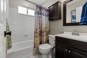 Bathroom with shower / bathtub combination with curtain, vanity, and tile patterned flooring
