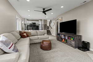 Living area with carpet floors, recessed lighting, ceiling fan, plenty of natural light, and stairs