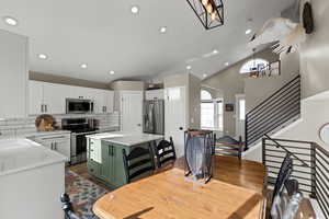 Kitchen with white cabinetry, appliances with stainless steel finishes, green cabinets, backsplash, and recessed lighting
