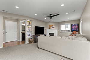Carpeted living room with ceiling fan, recessed lighting, and a brick fireplace