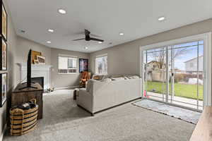 Living room featuring carpet floors, recessed lighting, ceiling fan, and a glass covered fireplace