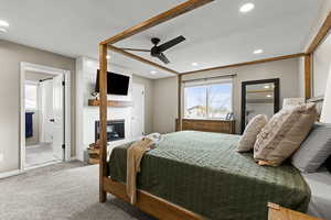 Bedroom featuring connected bathroom, carpet flooring, ceiling fan, a fireplace, and recessed lighting