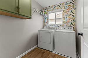 Laundry room with cabinet space, wood finished floors, separate washer and dryer, and wallpapered walls