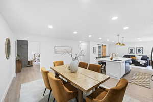 Dining room featuring a barn door, light wood-type flooring, and recessed lighting