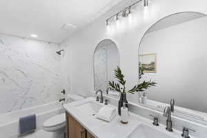 Full bath with double vanity, shower / tub combination, and a textured ceiling