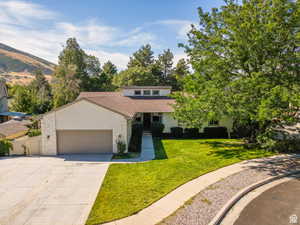 View of front of house featuring an attached garage, a front lawn, and concrete driveway