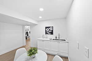 Bar featuring white cabinets, light wood-style flooring, recessed lighting, and light stone countertops