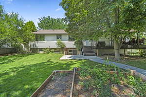 Rear view of house featuring a patio, stairs, a wooden deck, a vegetable garden, and a fenced backyard