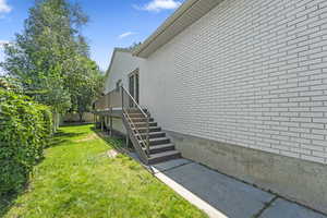 View of home's exterior featuring stairs, a yard, and brick siding