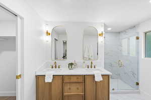 Bathroom with double vanity, a marble finish shower, a spacious closet, and recessed lighting