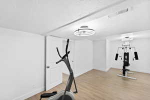Exercise room featuring a textured ceiling and light wood-style flooring