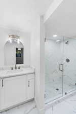 Full bath with light marble finish flooring, vanity, a marble finish shower, and a textured ceiling