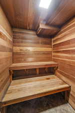Relaxing sauna featuring wooden ceiling, wood walls, and tile patterned floors