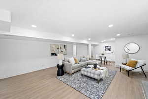 Living room with light wood-style flooring and recessed lighting