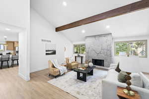 Living area with light wood-style floors, healthy amount of natural light, beamed ceiling, recessed lighting, and a fireplace