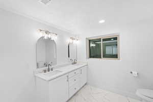 Full bath featuring double vanity, light marble finish flooring, recessed lighting, and a textured ceiling