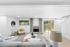Living area featuring stairway, wood finished floors, a brick fireplace, and recessed lighting