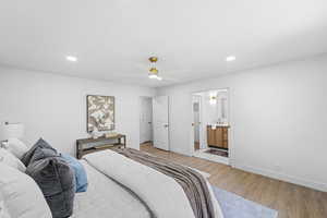 Bedroom with light wood-type flooring, ensuite bathroom, ceiling fan, and recessed lighting