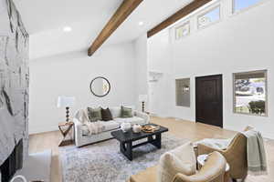 Living room with light wood-style floors, a fireplace, high vaulted ceiling, and beamed ceiling