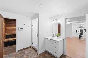Full bath with a sauna, vanity, and a marble finish shower
