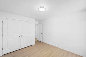 Unfurnished bedroom featuring light wood-type flooring, a closet, and a textured ceiling