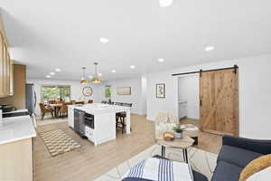 Living area with recessed lighting, light wood finished floors, and a barn door