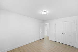 Unfurnished bedroom with light wood finished floors, a textured ceiling, and a closet